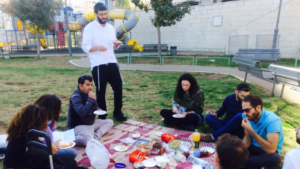 Tour participants nosh and share ideas near a Givat Shaul playground. Photo credit: Miriam Fisher